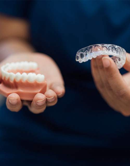 A medium close up of an orthodontist who is showing a patient some options for dental treat meant from their practice in the North East of England. Being shown are dental aligners and fixed braces.